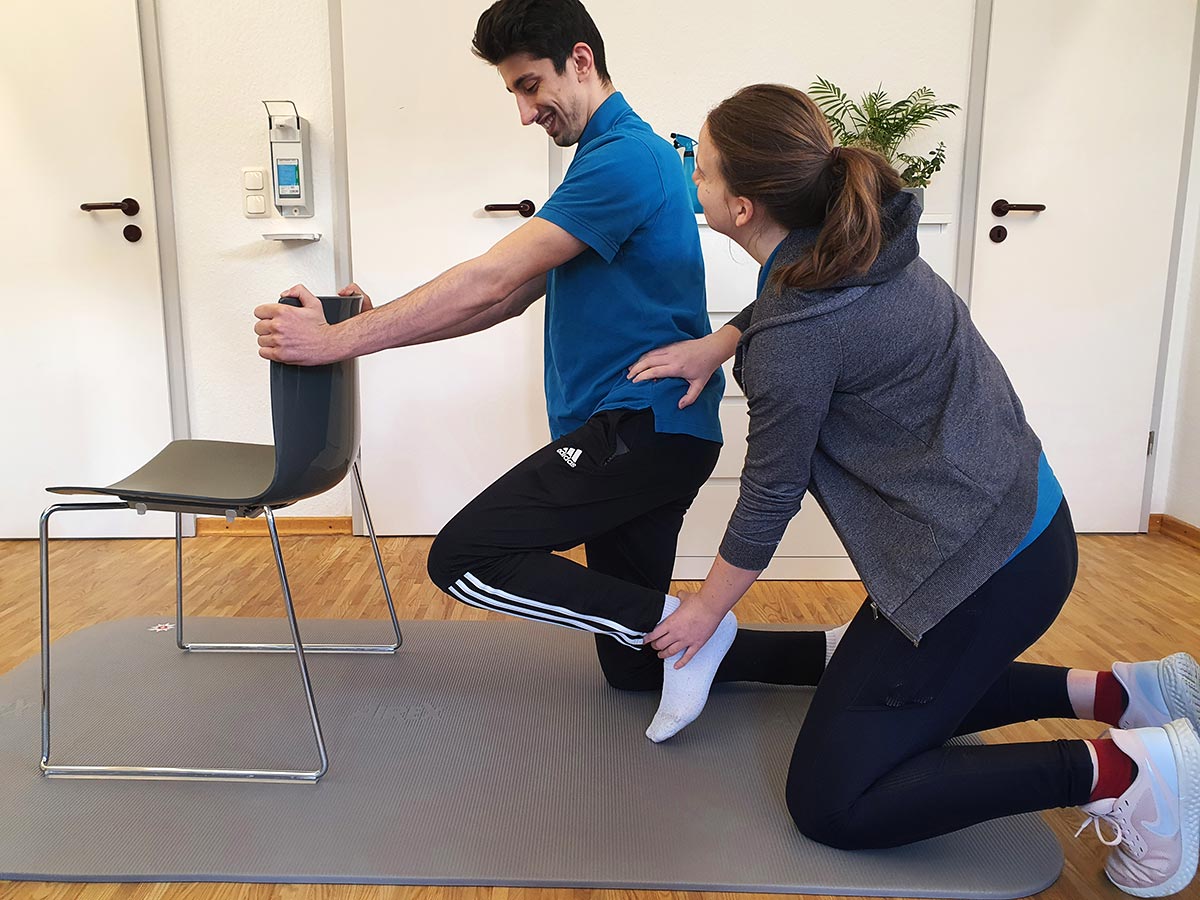 Physiotherapeutin unterstützt einem Patienten bei einer Übung der Krankengymnastik-ZNS